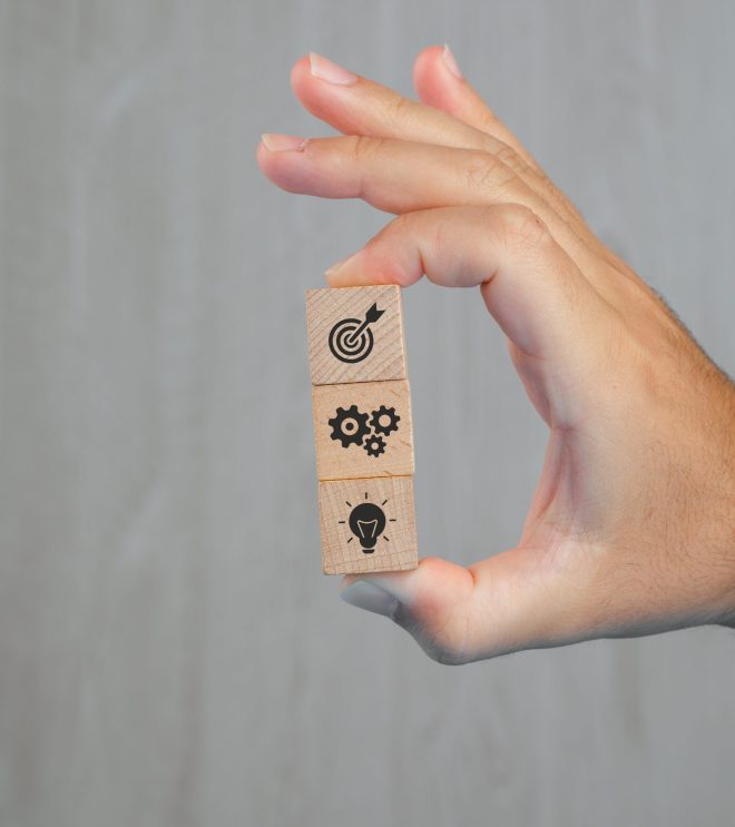 Business concept on grey background side view. hand holding wooden cubes with icons.